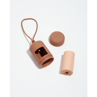 Poop Bag Carrier Dispenser in nude pink silicone with strap and removable cap; includes rolled bag refill