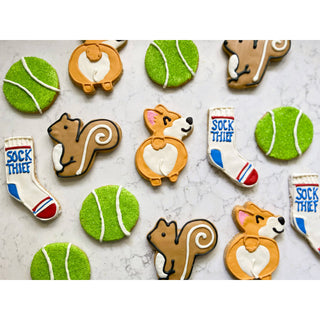 All the Dog Things Dapper cookies, assorted brown dog, orange corgi, squirrel, white socks, and green tennis-ball shapes.