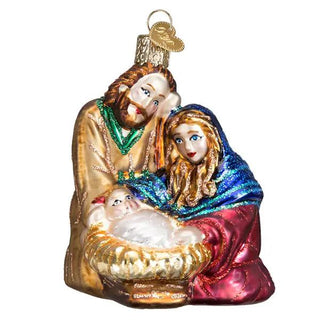 Holy Family ornament showing Mary, Joseph, and baby Jesus in a manger; glass figurine with gold, blue, and red accents.