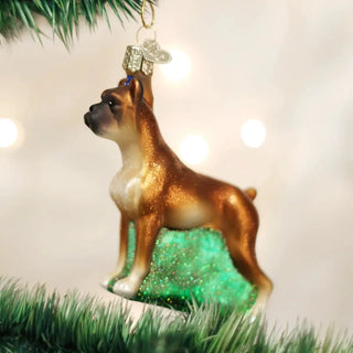 Boxer ornament on a Christmas tree, brown and white figure atop glittery green base.