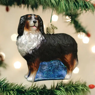 Bernese Mountain Dog ornament hanging on a Christmas tree; tri-color coat with glittery blue base and sparkling details.