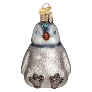 Sitting penguin chick ornament in silver-gray with glitter, blue eyes, orange beak, and gold hanging cap.