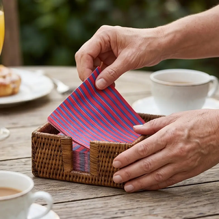 Rattan cocktail napkin holder in natural finish with pink and blue striped napkins