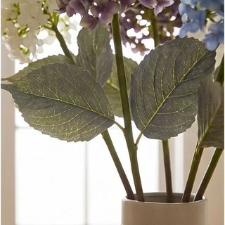 Cone Hydrangea Stem artificial flower with green leaves in a ceramic pot and blue, purple, and white blooms.