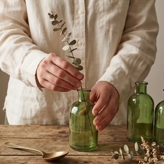Green glass bottles, set of 3 vases on a rustic wooden table with eucalyptus sprigs.