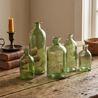 Green glass bottles of various sizes arranged on a rustic wooden table