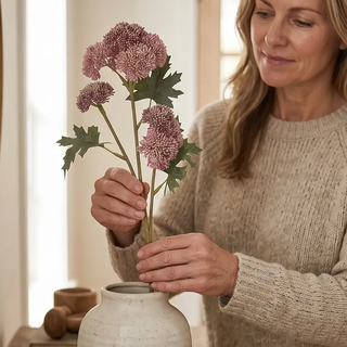 Pink sedum stems artificial plant with pink flower clusters and green leaves in a beige ceramic vase