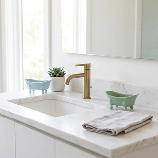 Bathtub soap dish set of two in mint green and pale blue with claw feet on a white marble vanity.