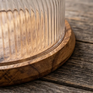 Glass cloche with ribbed dome on a round wooden base.
