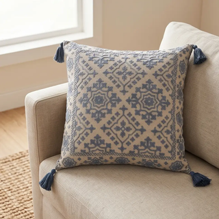 Handcrafted square pillow in beige with blue embroidered pattern and tassel corners
