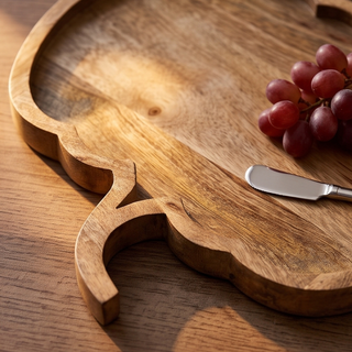 Mango wood pumpkin-shaped cheese/serving board, natural finish, with a cheese knife and grapes nearby