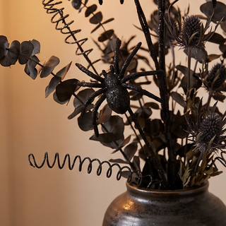 Black glitter spider spray arrangement with curly stems in a metallic vase