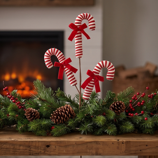 Pink peppermint spray: three red-and-white striped candy canes with red bows amid evergreen garland and pinecones.