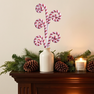 Peppermint Swirl Spray in cream vase with five red-and-white candy-cane stems and pinecones on a mantel with candle.