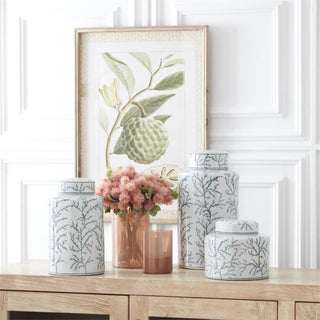 Set of five white ceramic ginger jars with green coral patterns on a wooden surface.
