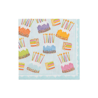 Cocktail napkin with cake-frosting designs and colorful sprinkles on a light blue striped paper linen background.