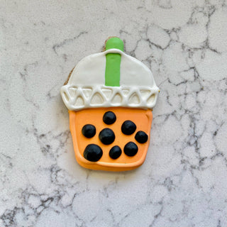 Lunch Menu Dapper cookie shaped like a bubble tea cup; orange cup with black tapioca pearls, white lid, and green straw