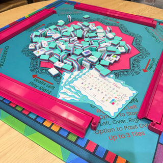 Lunaflor Mahjong Mat with teal play surface and pink border, scattered mint-green Mahjong tiles