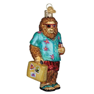 Sasquatch Gone Tropics ornament: Bigfoot in turquoise shirt, red shorts, sunglasses, carrying a yellow suitcase.