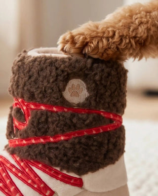 Apres Ski Boot squeaker dog toy, brown plush boot with red straps and paw patch.