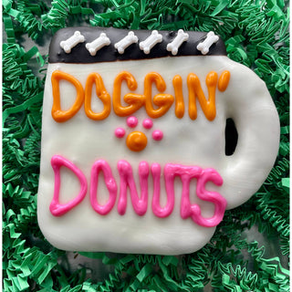 Dogging Donuts coffee dog treats cookie with orange DOGGIN’ lettering and pink DONUTS icing