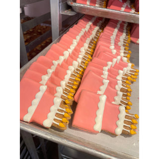 Dapper pink birthday dog biscuits with white bone icing trim and yellow accents
