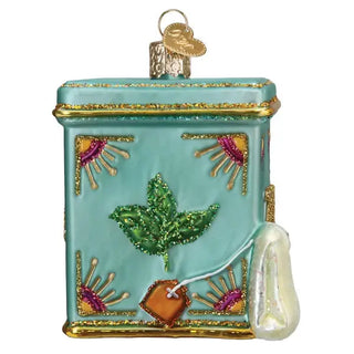 Tea tin ornament in turquoise with gold trim and glitter, featuring a hanging teabag charm.
