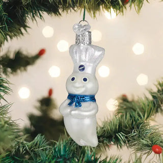 Doughboy ornament hanging on a Christmas tree; white figure with a silver chef hat and blue ribbon scarf.