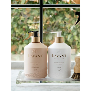 Two pump-dispense dish soap bottles in pale pink and white with gold neck bands on a clear tray.