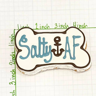Bone-shaped dog treat with white icing, blue Salty AF lettering and anchor symbol