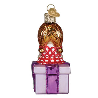 Misfit doll ornament on a purple gift box with red checkered scarf and gold top