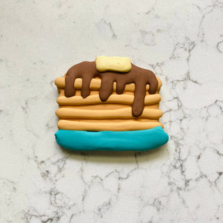 Breakfast Menu Dapper pancake cookie for pets; beige stack with brown drizzle and turquoise base.