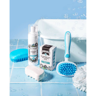 Deodorizing shampoo bottle with rinse-free foaming formula in blue and white, part of a grooming set with brush
