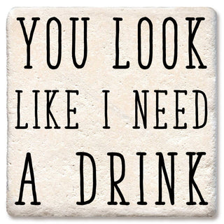 Coaster beige stone-look with bold black lettering reading YOU LOOK LIKE I NEED A DRINK