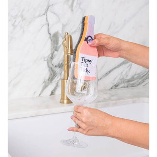Scrubbly sponge Tipsy, a colorful multi-layer scrub sponge cleaning a wine glass