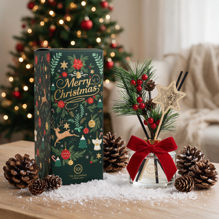 Pine Cone Snowflake Holiday Reed Diffuser, 6.9oz, glass bottle with red bow beside green Merry Christmas box.