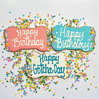 Dapper dog birthday cookies: three bone-shaped treats in pink, blue, and white with colorful sprinkles