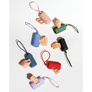 Dapper silicone poop bag carrier dispenser in assorted colors with strap and protruding bags.