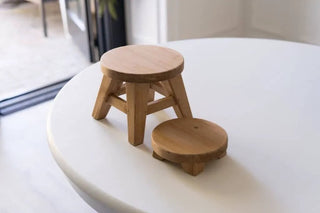 6x6x2in natural wood round mini riser set; two pieces on white table (one legged stool, one flat disk)