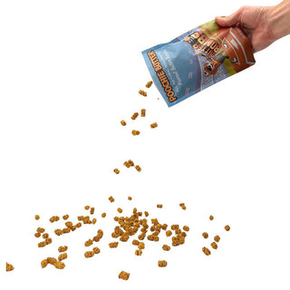 Peanut Butter Crunchy Dog Treats 8oz by Poochie Butter, crunchy bite-sized pieces pouring from a blue bag