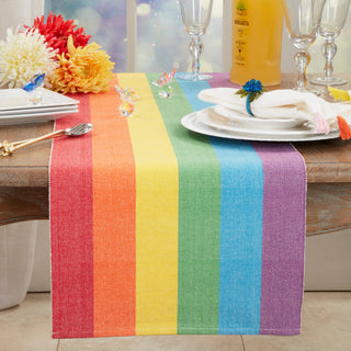 Rainbow Stripe Delight Table Runner on a wooden table with white plates, napkin and glassware.