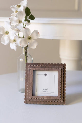 Wood scallop photo frame, espresso finish, 4x4 inches, displayed on a table with a glass vase of white flowers.