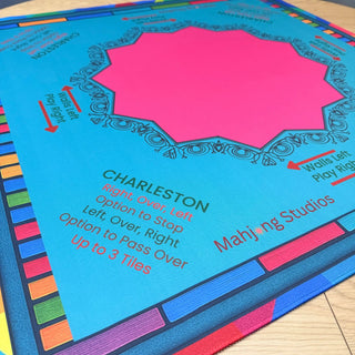Lunaflor Mahjong Mat with pink octagonal center on bright blue surface and multicolor border