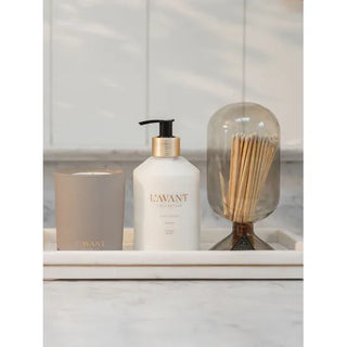 Candle Ambre Santal in a taupe jar on a tray with a pump bottle and a glass cloche with reeds, three-item display