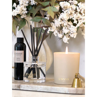 Candle Ambre Santal; cream-beige candle with gold lettering beside black diffuser bottle and glass reed diffuser jar