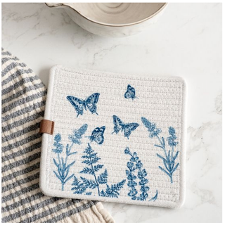 Butterfly square pot holder in white quilted fabric with blue butterfly and botanical print; brown loop strap