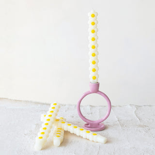 Daisy-shaped taper candles, unscented, cream with yellow centers, 10-inch, set of 2 on pink candle holder.