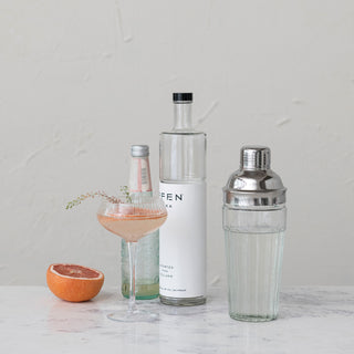 Glass cocktail shaker with stainless steel top, clear glass body; barware scene with Effen vodka bottle.