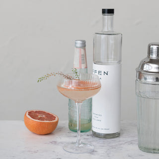 Glass and metal cocktail shakers on a marble bar; two pieces with stainless steel tops.