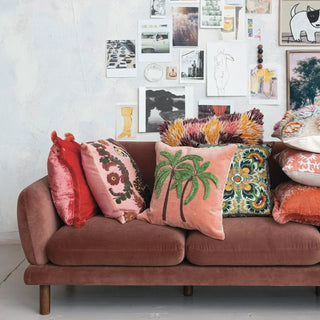 Pillow, 20-inch square cotton slub with tiger and flower embroidery, displayed among colorful cushions on a rust sofa.